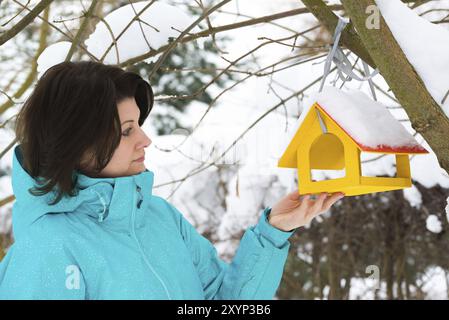 Femme se tient près d'une mangeoire pour oiseaux jaune Banque D'Images