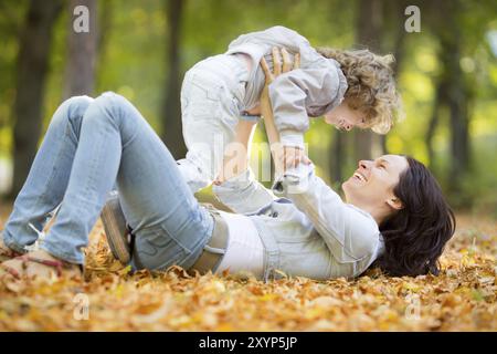 Bonne famille s'amuser en plein air dans le parc d'automne contre flou laisse l'arrière-plan Banque D'Images