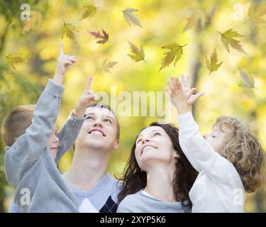 Bonne famille s'amuser en plein air dans le parc d'automne contre flou laisse l'arrière-plan Banque D'Images