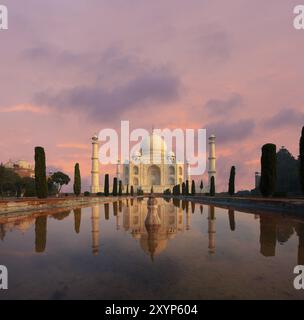 Personne présent comme Taj Mahal brille magnifiquement au coucher du soleil reflété dans la piscine de fontaine d'eau de jardin avant sous un ciel rose dramatique à Agra, Utta Banque D'Images