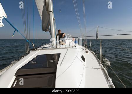 Skipper est assis sur le pont supérieur de son yacht à voile Banque D'Images