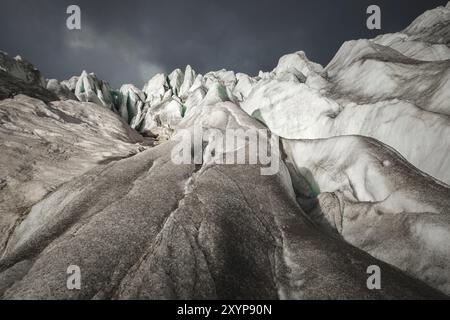 La fissure de gros plan est une fissure bleu profond qui se trouve dans la glace et la boue noire sur le glacier. Grand angle et ciel spectaculaire Banque D'Images