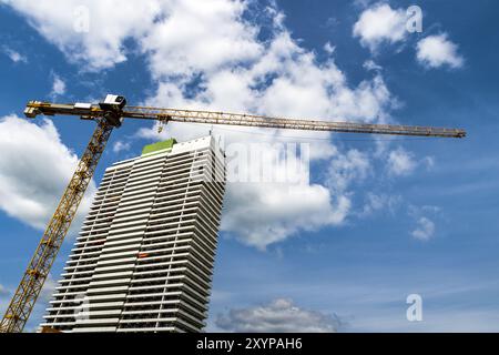 Une grue et un gratte-ciel contre un ciel bleu Banque D'Images