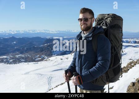 Portrait d'un heureux riant voyageur Hipster avec une barbe dans des lunettes de soleil dans la nature. Un homme randonnant dans les montagnes avec un sac à dos et scandinave Banque D'Images