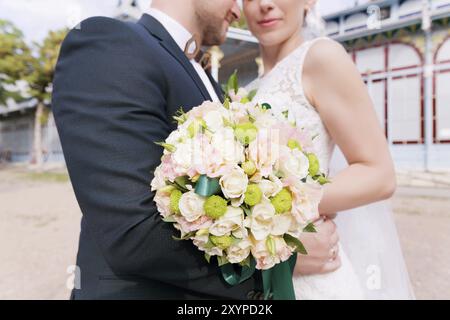 Portrait d'un bouquet de mariage sur le fond Un beau couple de jeunes mariés qui se tient dans les bras sur le fond du bâtiment vintage de Banque D'Images