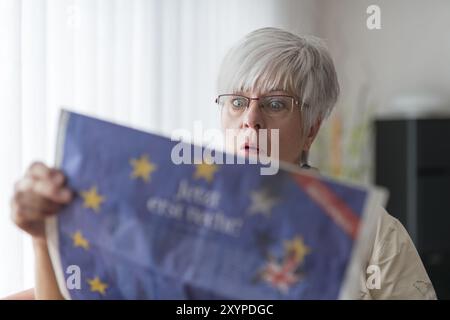 Une dame âgée lit les nouvelles du Brexit et ouvre les yeux sous le choc Banque D'Images