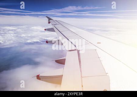 Vue d'une aile grise d'avion à travers la fenêtre de l'avion. Soleil, réchauffement climatique Banque D'Images