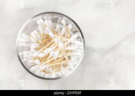 Une photo prise à la verticale du bambou coton-tiges dans un bocal de verre sur une surface en marbre avec une place pour le texte Banque D'Images