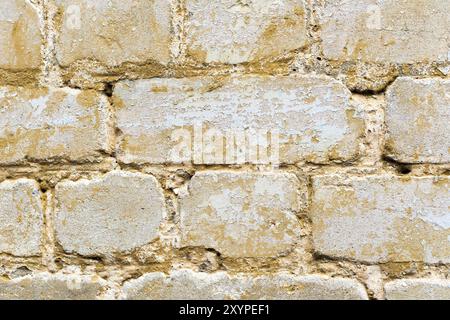 Fond texturé d'une brique multicolore peinte en jaune. Une peinture jaune grésillante sur une vieille brique cassée. Style grunge Banque D'Images