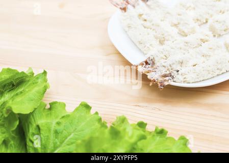 Crevettes crues dans de la chapelure près d'une salade de légumes frais gros plan sur une assiette sur une table. Nourriture maison savoureuse et saine Banque D'Images