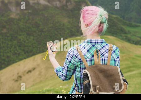 Une jeune fille hipster a voyagé avec un blogueur dans une chemise à carreaux et avec des cheveux multicolores en utilisant une boussole en arrière-plan dans le fond du Caucasi Banque D'Images