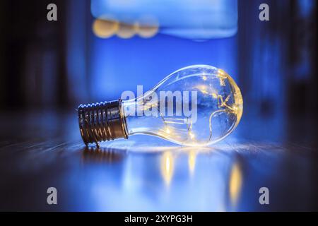 L'ampoule LED repose sur le plancher en bois. Symbole des idées et de l'innovation. Fenêtre et lumière dans l'arrière-plan flou Banque D'Images