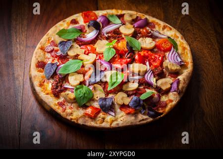 Pizza maison avec tomates séchées, salami et basilic Banque D'Images