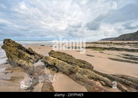Les rochers anciens émergent à marée basse sur la plage de Sandymouth North West Cornwall à l'aube Banque D'Images