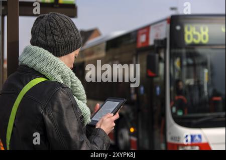 Jeune femme lisant un eBook à un arrêt de bus Banque D'Images