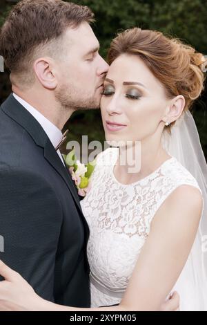 Portrait en gros plan d'un couple adorable de jeunes mariés sur fond de greens d'été. Le concept de la vie heureuse de Hipster dans le mariage Banque D'Images