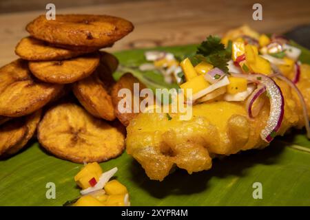 Un délicieux plat de poisson frit et d'inspiration ouest-africaine Frites avec tranches de banane frites servies sur une feuille de banane Banque D'Images