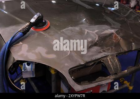 Photo stock de ponceuse pneumatique orbitale de palme pneumatique sur un capot de voiture dans un atelier de réparation Auto atelier outil de réparation horizontal Banque D'Images