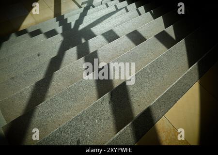 Ombre d'une grille de fenêtre sur les marches d'un escalier dans une cage d'escalier Banque D'Images