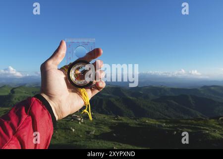 Homme cherchant la direction avec un compas dans sa main dans le point de vue des montagnes d'été. Recherche de direction Banque D'Images