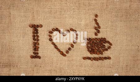 Conceptuel artistique nature morte de I Love Coffee signe motif sur tissu rustique en toile de jute fabriqué par des grains de café. Arrière-plan symbolique Banque D'Images