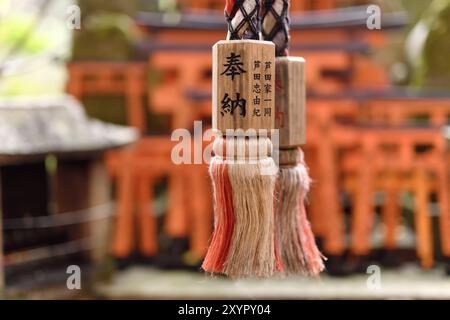 Gros plan d'une corde de Suzu, cloche de sanctuaire shinto japonais avec offrande écrite dessus au sanctuaire Fushimi Inari à Kyoto, Japon, Asie Banque D'Images