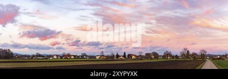 Panorama, coucher de soleil sur les champs et village autrichien avec ciel spectaculaire et nuages colorés Banque D'Images