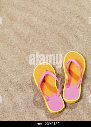 Gros plan d'une paire de tongs orange sur fond de sable de plage Banque D'Images