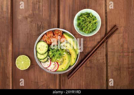 Une photo prise à la verticale de poke, Hawaïen traditionnel salade de poisson cru, avec une assiette de légume de mer, wakamé, avec des baguettes, limes, et copy space Banque D'Images