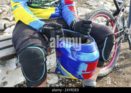 Gros plan coureur masculin MTB cycliste en tenue de protection se préparer pour la course tenant le casque intégral Banque D'Images