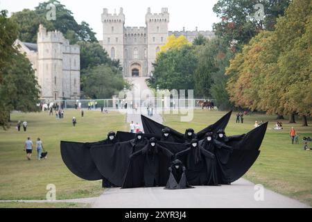 Windsor, Royaume-Uni. 30 août 2024. Extinction Rebellion a organisé une manifestation sur la longue marche avec pour toile de fond le château de Windsor à Windsor, Berkshire ce soir. Les manifestants climatiques de XR portaient des costumes d'affaires et s'habillaient en barons du pétrole, en magnats des médias et en financiers sans visage. Les Oil Slicks, habillés de costumes noirs avec de la peinture de visage noir et blanc, ont réalisé une action théâtrale chorégraphiée dans le but de mettre en évidence le récit XR pour la journée, que le système est brisé. Les rebelles XR campent à Home Park en face du château de Windsor aujourd'hui et pendant le week-end dans le cadre de leur surclassement de trois jours Banque D'Images