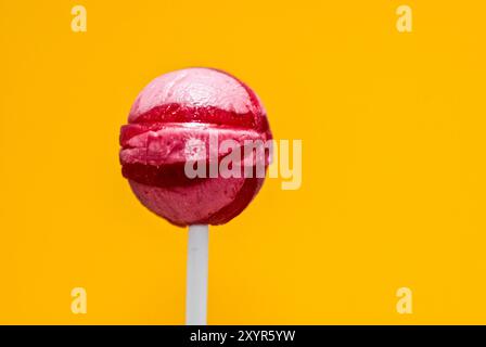 Bonbons en lollypop rose isolé sur jaune avec un espace texte Banque D'Images