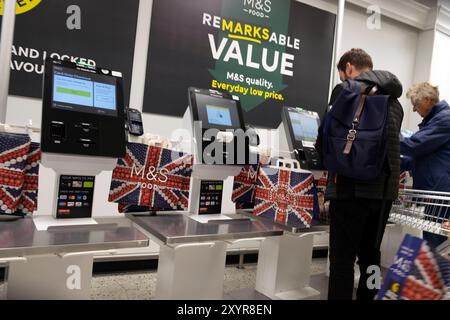 Supermarché Marks and Spencer à l'intérieur des clients payant aux caisses libre-service scanners avec sacs à provisions en papier Union Jack Oxford UK 2024 Banque D'Images