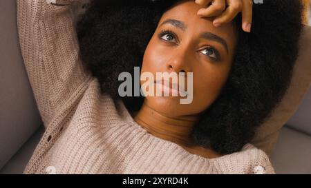 Solitaire triste femme afro-américaine déprimée couchée sur le canapé seul à la maison malheureuse fille paresseuse fatiguée apathique femme se relaxant sur la dépression du canapé Banque D'Images