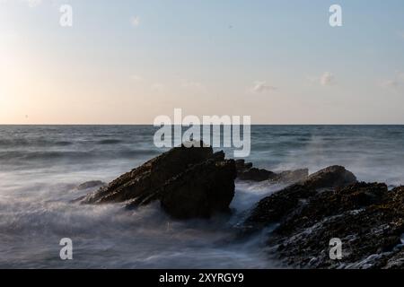 Les vagues s'écrasent sur les rochers au coucher du soleil sur newquay Beach, cornwall, une destination de surf populaire Banque D'Images