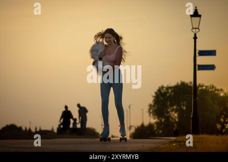 Londres, Royaume-Uni. 30 août 2024. Météo britannique : Kristi et son chien Poméranie 'Choopi' patinent ensemble en profitant d'un vendredi soir chaud alors que le soleil se couche sur Blackheath. Crédit : Guy Corbishley/Alamy Live News Banque D'Images