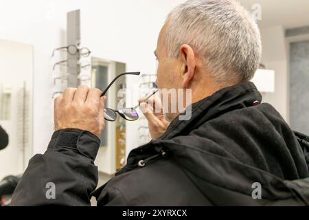 Homme senior choisissant des lunettes à la clinique opticienne. Banque D'Images