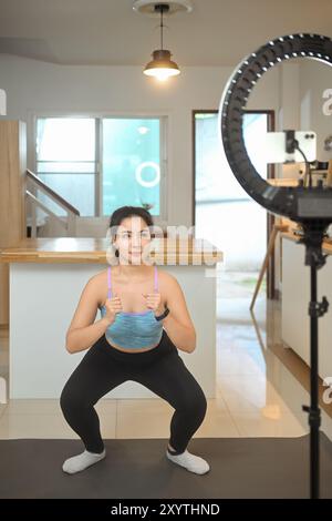 Jeune femme dans le sport porter l'enregistrement d'une vidéo d'entraînement ou participer à un cours de fitness virtuel Banque D'Images