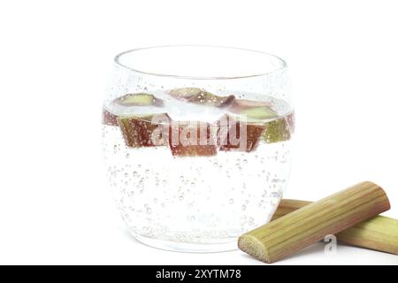 Verre transparent rempli d'eau froide et de plusieurs morceaux de rhubarbe isolé sur fond blanc Banque D'Images