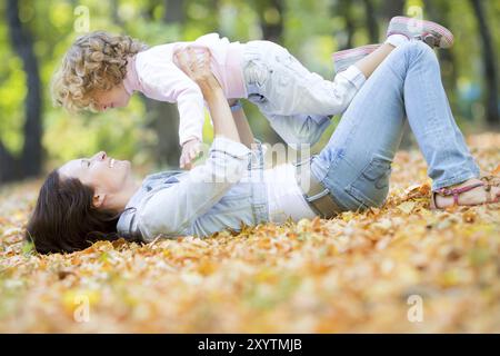 Bonne famille s'amuser en plein air dans le parc d'automne contre flou laisse l'arrière-plan Banque D'Images