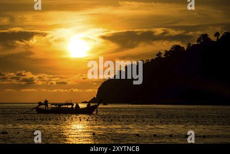 Vue sur le coucher du soleil depuis la plage de Pattaya à Ko Lipe, Thaïlande montre un bateau longtail conduisant devant le soleil couchant Banque D'Images