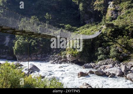 Pont suspendu traversant une rivière dans la région de l'Annapurna au Népal Banque D'Images