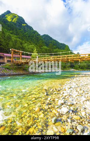 Touristes japonais marchant sur le pont Kappa-Bashi vu de bas angle à côté des rochers de la rivière Azusa-gawa pendant la lumière spectaculaire tôt le matin à Kamikoc Banque D'Images