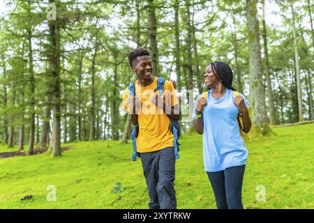 Photo colorée de trois quarts de longueur de deux jeunes amis africains marchant le long d'une forêt Banque D'Images