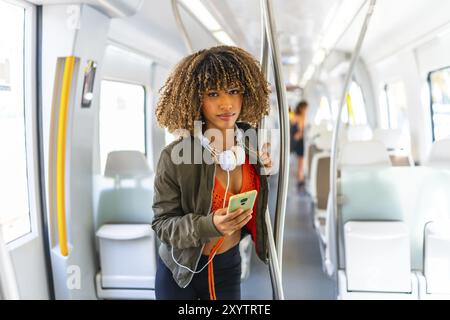 Portrait d'une jeune femme latine de beauté debout dans le métro tout en utilisant le téléphone Banque D'Images