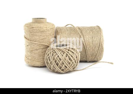 Trois bobines de ficelle de jute isolées sur fond blanc, chacune variant en taille, fabriquées à partir de matériaux naturels de jute Banque D'Images