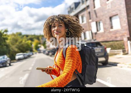 Vue latérale d'une femme latine de beauté marchant le long de la rue en utilisant le téléphone portable pour obtenir des directions avec gps Banque D'Images