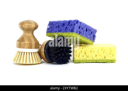 Éponges, chacune d'une couleur différente violet, jaune et deux brosses avec des poignées en bois isolées sur fond blanc, outils de nettoyage Banque D'Images