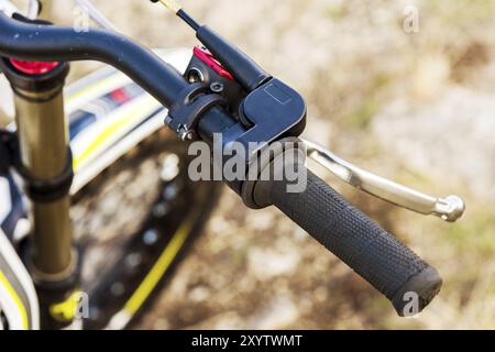 Gros plan de la poignée du volant dirigeant une moto d'essai avec frein sur fond d'herbe jaune Banque D'Images