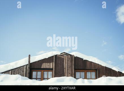 Maison moderne en bois en hiver : neige sur le toit, ciel bleu Banque D'Images